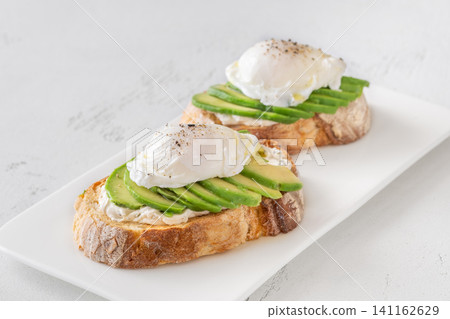 Avocado toast with poached eggs on artisan bread plate Avocado toast with poached eggs on artisan bread plate 141162629