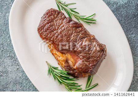 Perfectly grilled beef steak with rosemary on white plate premium restaurant presentation Perfectly grilled beef steak with rosemary on white plate premium restaurant presentation 141162641