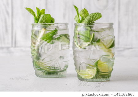 Two fresh mojito cocktails in tiki glasses with lime mint garnish Two fresh mojito cocktails in tiki glasses with lime mint garnish 141162663