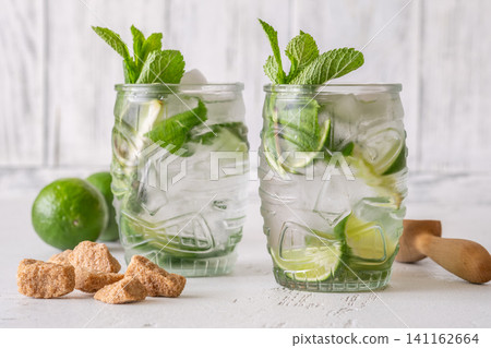 Two fresh mojito cocktails in tiki glasses with lime mint garnish Two fresh mojito cocktails in tiki glasses with lime mint garnish 141162664