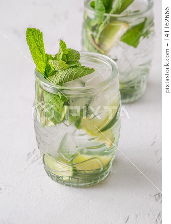 Two fresh mojito cocktails in tiki glasses with lime mint garnish Two fresh mojito cocktails in tiki glasses with lime mint garnish 141162666