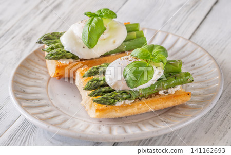 Gourmet Asparagus Bruschetta Topped With Perfectly Poached Eggs And Fresh Basil Leaves Gourmet Asparagus Bruschetta Topped With Perfectly Poached Eggs And Fresh Basil Leaves 141162693