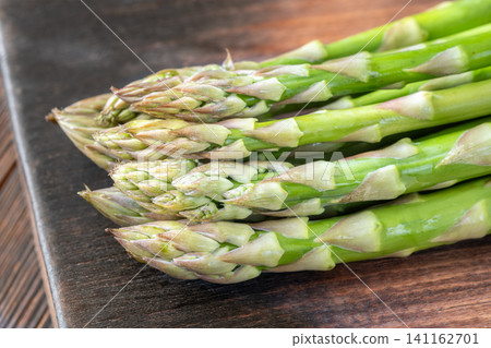 Fresh Green Asparagus Buds Macro Close Up On Dark Rustic Wooden Board Fresh Green Asparagus Buds Macro Close Up On Dark Rustic Wooden Board 141162701