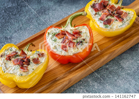 Stuffed Bell Peppers With Bacon Garnish On Rustic Serving Board Stuffed Bell Peppers With Bacon Garnish On Rustic Serving Board 141162747