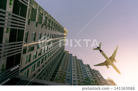 Airplane flying above modern apartment building. Exterior facade of skyscraper building. Business trip. Transparent glass windows of apartment. Aviation business after coronavirus vaccine injection. Airplane flying above modern apartment building. Exterior facade of skyscraper building. Business trip. Transparent glass windows of apartment. Aviation business after coronavirus vaccine injection. 141163088