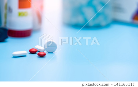 Selective focus on round white and red tablets pills on blur plastic drug bottle. Pharmacy drugstore products. Pharmaceutical industry. Health budget and health insurance background. Polypharmacy. Selective focus on round white and red tablets pills on blur plastic drug bottle. Pharmacy drugstore products. Pharmaceutical industry. Health budget and health insurance background. Polypharmacy. 141163115