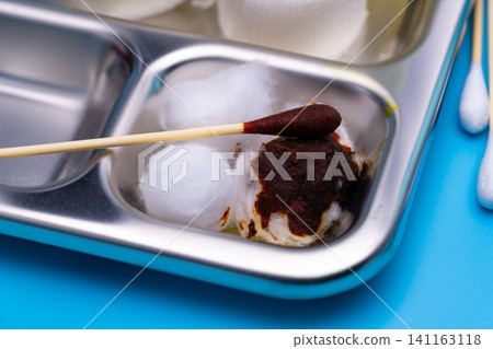 Wound care dressing set and stainless steel plate on blue background. Cotton ball and cotton stick with povidone-iodine for wounds, burns and cuts. Wound care supplies. Medical equipment for nurse. Wound care dressing set and stainless steel plate on blue background. Cotton ball and cotton stick with povidone-iodine for wounds, burns and cuts. Wound care supplies. Medical equipment for nurse. 141163118