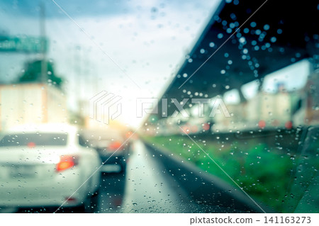 Rain drops on windshield. Car driving on asphalt road on rainy day. Windshield window of car with raindrops on glass windscreen. Traffic jam on rainy season. Bad weather in stormy day. Travel by car. 141163273