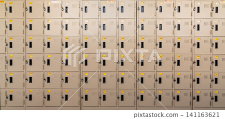 Closeup beige locker with lock and numbered yellow tags at locker room. Locker for safety and security storage. Row of locker with locked door background. Closeup beige locker with lock and numbered yellow tags at locker room. Locker for safety and security storage. Row of locker with locked door background. 141163621
