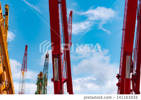 Crawler crane against blue sky and white clouds. Real estate industry. Red crawler crane use reel lift up equipment in construction site. Crane for rent. Crane dealership for construction business. Crawler crane against blue sky and white clouds. Real estate industry. Red crawler crane use reel lift up equipment in construction site. Crane for rent. Crane dealership for construction business. 141163838