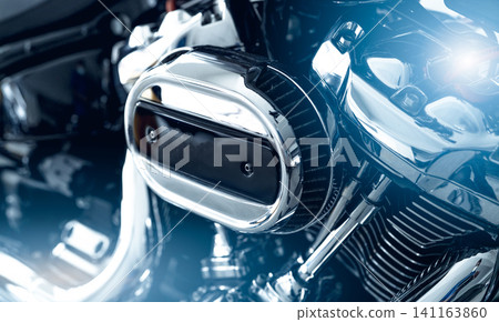 Selective focus on a motorcycle air filter with blur engine and shiny exhaust pipe. Motorcycle dealership business. Shiny chrome motorbike engine and exhaust pipe. Closeup vintage motorbike parts. Selective focus on a motorcycle air filter with blur engine and shiny exhaust pipe. Motorcycle dealership business. Shiny chrome motorbike engine and exhaust pipe. Closeup vintage motorbike parts. 141163860