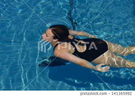 Teen girl swimming underwater in clear outdoor pool water Teen girl swimming underwater in clear outdoor pool water 141163992