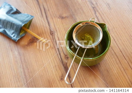 Sifting matcha powder into bowl for homemade iced latte recipe Sifting matcha powder into bowl for homemade iced latte recipe 141164314