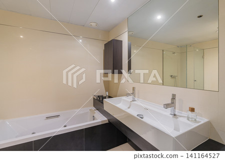 Contemporary bathroom interior with white built in bathtub, double sink vanity, large wall mirror, chrome fixtures, bright neutral finishes, spacious modern residential design Contemporary bathroom interior with white built in bathtub, double sink vanity, large wall mirror, chrome fixtures, bright neutral finishes, spacious modern residential design 141164527