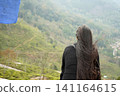 Young woman with long hair looking out over a scenic tea plantation landscape 141164615