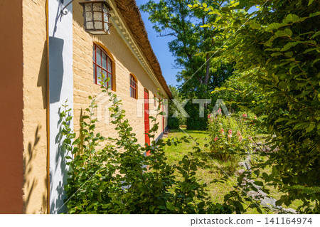 Historic yellow farmhouse in sunny summer garden Historic yellow farmhouse in sunny summer garden 141164974