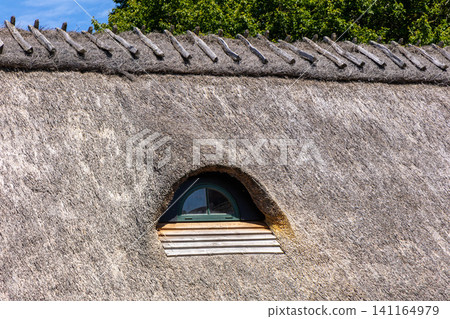 Traditional thatched roof with small arched window Traditional thatched roof with small arched window 141164979