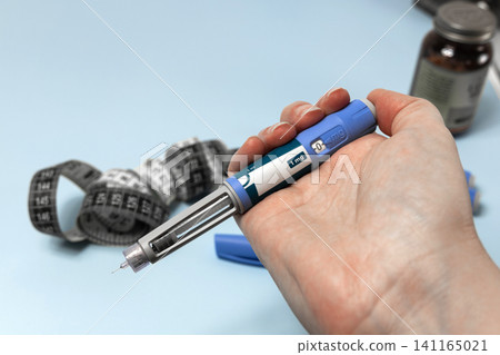 Hand holding Ozempic injection pen for diabetes treatment. 141165021
