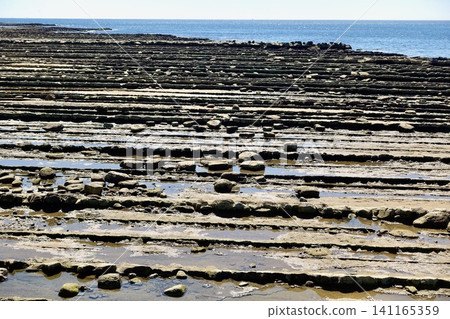 Under a clear blue sky, the Nichinan coast is covered in a spectacular display of wave-shaped rock formations known as "Oni no Sentakuita" (Devil's Washboard). Under a clear blue sky, the Nichinan coast is covered in a spectacular display of wave-shaped rock formations known as "Oni no Sentakuita" (Devil's Washboard). 141165359
