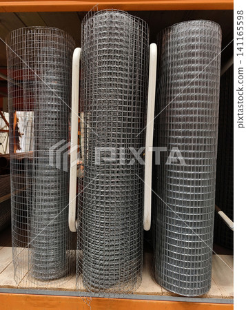 Welded metal mesh in large rolls arranged on a shelf for sale in a building hypermarket department Welded metal mesh in large rolls arranged on a shelf for sale in a building hypermarket department 141165598