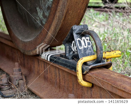 Freight wagon wheel locked on industrial railroad with steel brake chock for safety 141165629