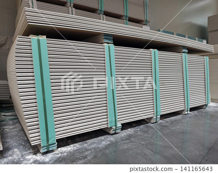 A large stockpile of gypsum boards ready for transportation in a construction warehouse 141165643