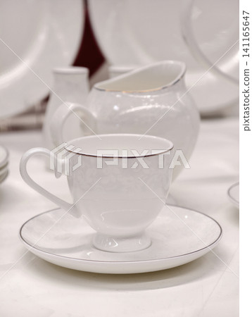 White porcelain cup on saucer in close up view from elegant tableware set showing refined glossy surface and minimal luxury design for premium retail presentation concept White porcelain cup on saucer in close up view from elegant tableware set showing refined glossy surface and minimal luxury design for premium retail presentation concept 141165647