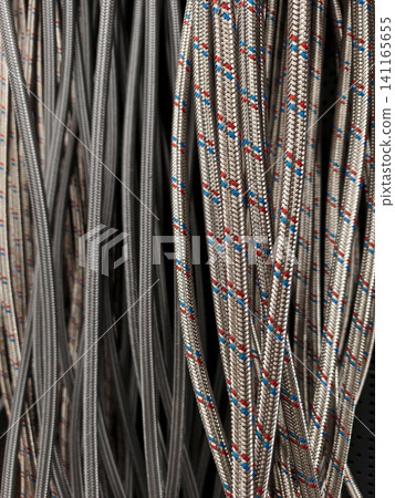 Nylon water hoses with stainless steel braided reinforcement presented on supermarket hooks in plumbing section Nylon water hoses with stainless steel braided reinforcement presented on supermarket hooks in plumbing section 141165655