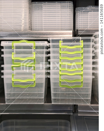 Plastic containers with green handles in large and small sizes stacked on retail shelves with lids placed separately nearby for modern organization solution Plastic containers with green handles in large and small sizes stacked on retail shelves with lids placed separately nearby for modern organization solution 141165689