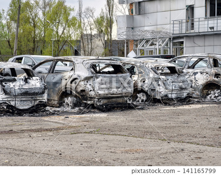 Burnt wrecks of vehicles in a parking lot after missile strike. Missile strike reduces parked cars to smoldering wreckage 141165799