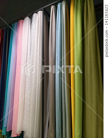 Bright, multicolored curtains arranged on display for customers inside a shop Bright, multicolored curtains arranged on display for customers inside a shop 141165825