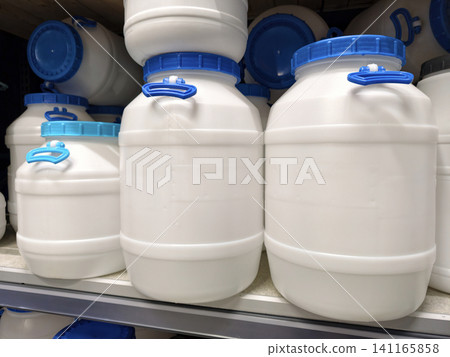 Various sized barrels with blue lids in different shapes are neatly arranged on shelves in a hardware store, available for sale Various sized barrels with blue lids in different shapes are neatly arranged on shelves in a hardware store, available for sale 141165858