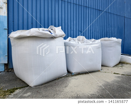 Large sandbags stacked outside the warehouse entrance, ready for use in emergencies Large sandbags stacked outside the warehouse entrance, ready for use in emergencies 141165877