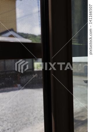 透過紗門看到的窗外景色。紗門的特寫。 透過紗門看到的窗外景色。紗門的特寫。 141166507