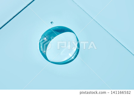 Transparent serum droplet falling on light blue surface Transparent serum droplet falling on light blue surface 141166582