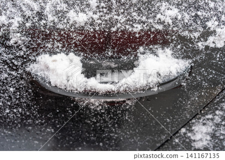 Close-up of a car door handle partially filled with snow and surrounded by frost. Close-up of a car door handle partially filled with snow and surrounded by frost. 141167135