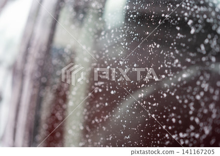 Close-up of a car window covered with scattered snowflakes and ice crystals. Close-up of a car window covered with scattered snowflakes and ice crystals. 141167205