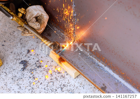 Person uses torch to cut metal in workshop at construction site Person uses torch to cut metal in workshop at construction site 141167257