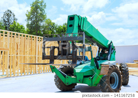 Construction vehicle telehandler lifts wooden trusses beams on building site Construction vehicle telehandler lifts wooden trusses beams on building site 141167258