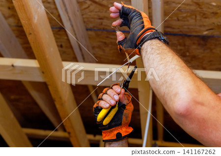 Worker uses pliers to cut wire while standing on construction site Worker uses pliers to cut wire while standing on construction site 141167262