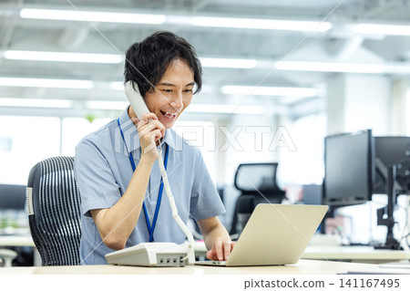 A businessman talking on a landline phone in the office A businessman talking on a landline phone in the office 141167495