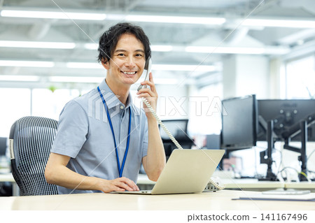 A businessman talking on a landline phone in the office A businessman talking on a landline phone in the office 141167496