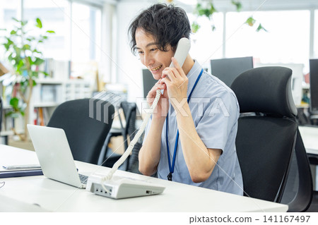 A businessman talking on a landline phone in the office A businessman talking on a landline phone in the office 141167497