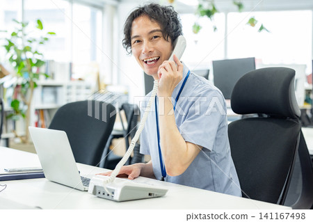 A businessman talking on a landline phone in the office A businessman talking on a landline phone in the office 141167498