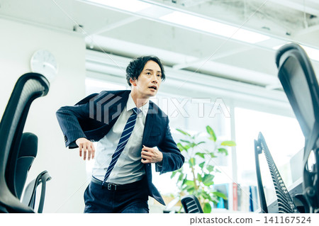 A male businessman in a suit starts running in the office. A male businessman in a suit starts running in the office. 141167524