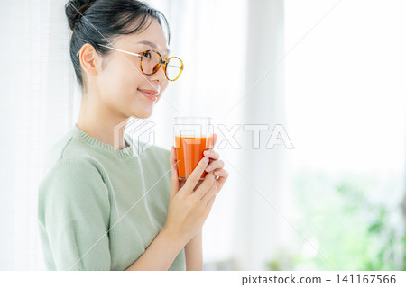 一位年輕女子正在喝番茄汁 141167566