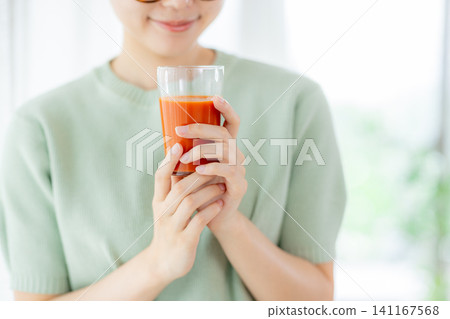 一位年輕女子正在喝番茄汁 141167568