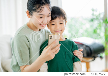 一個孩子和他們的母親在玩智慧型手機 一個孩子和他們的母親在玩智慧型手機 141167577