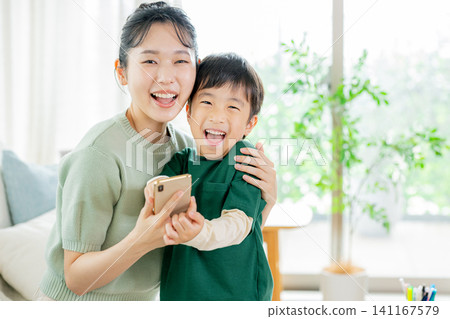 一個孩子和他們的母親在玩智慧型手機 一個孩子和他們的母親在玩智慧型手機 141167579