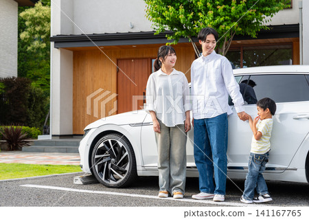 A family of three smiles and chats in front of their beloved car in the driveway of their home. A family of three smiles and chats in front of their beloved car in the driveway of their home. 141167765